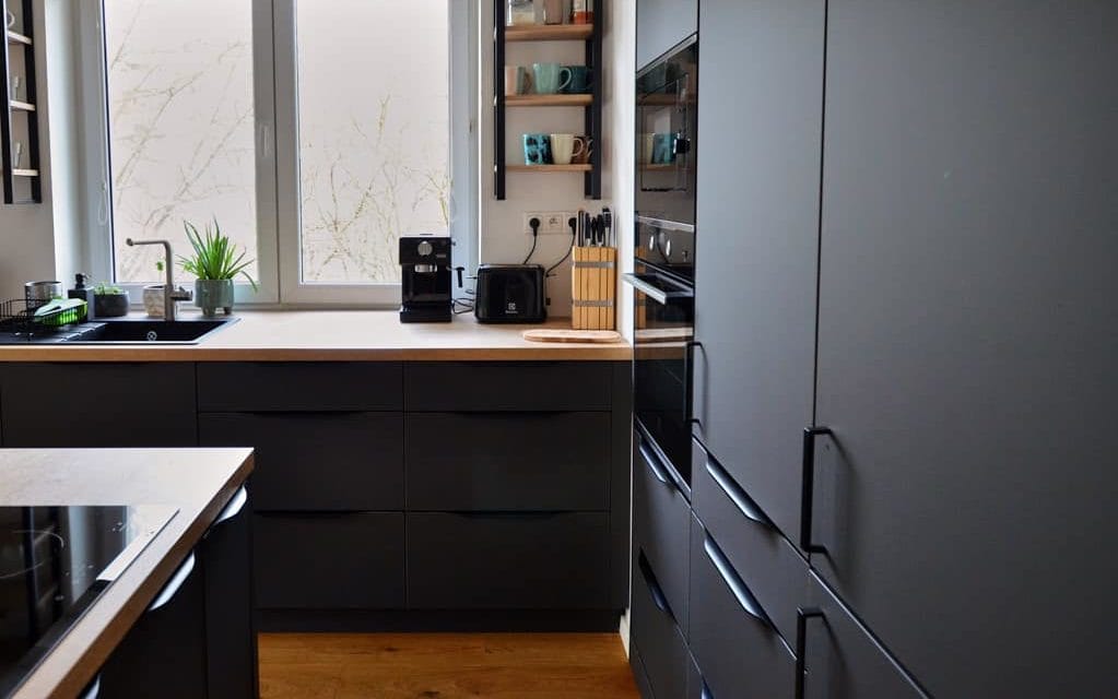 ČIERNA KUCHYŇA S DREVOM V MULTIFUNKČNOM PRIESTORE ČIERNE KUCHYNE, KUCHYNE S OSTROVČEKOM, LUXUSNÉ KUCHYNE, MATNÉ KUCHYNE, MODERNÉ KUCHYNE, ŠTÝLOVÉ KUCHYNE